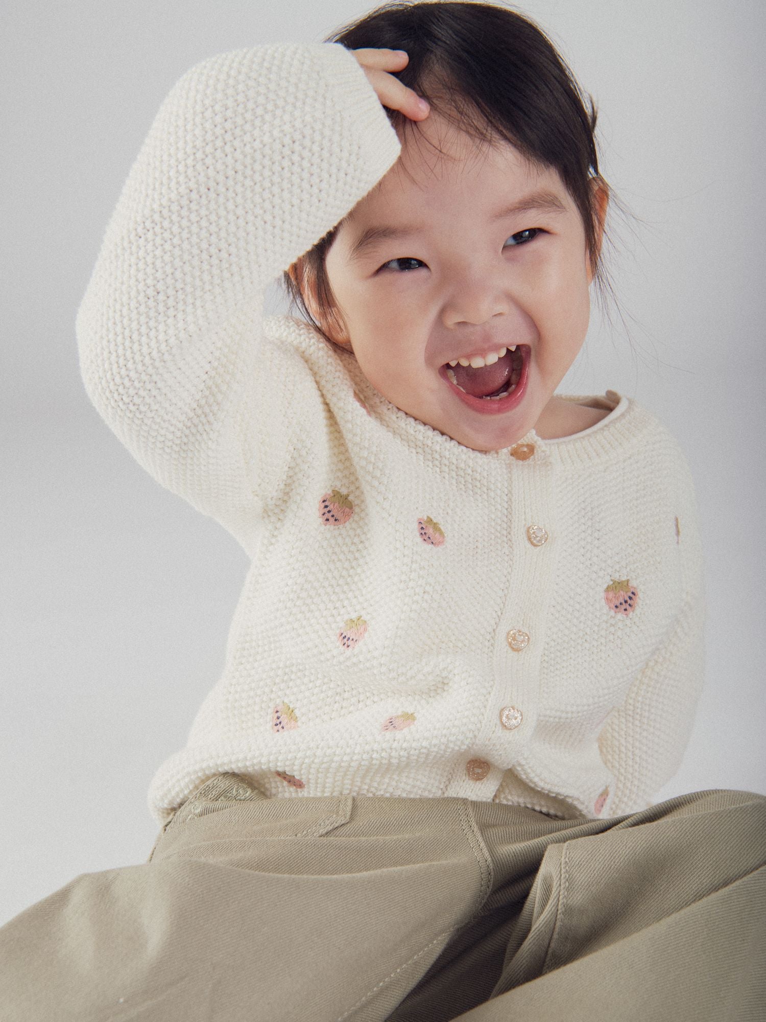 Cárdigan de punto ecru con brodería de fresa para bebé niña