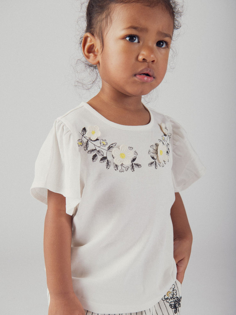 Camiseta ecru bordada con flores y mangas con volantes para niña
